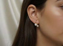 A model wearing Caellia 18K gold plated stud earrings featuring two freshwater pearls.