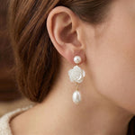 A model wears Caellia 14K gold dangle earrings featuring a camellia flower and freshwater pearl.
