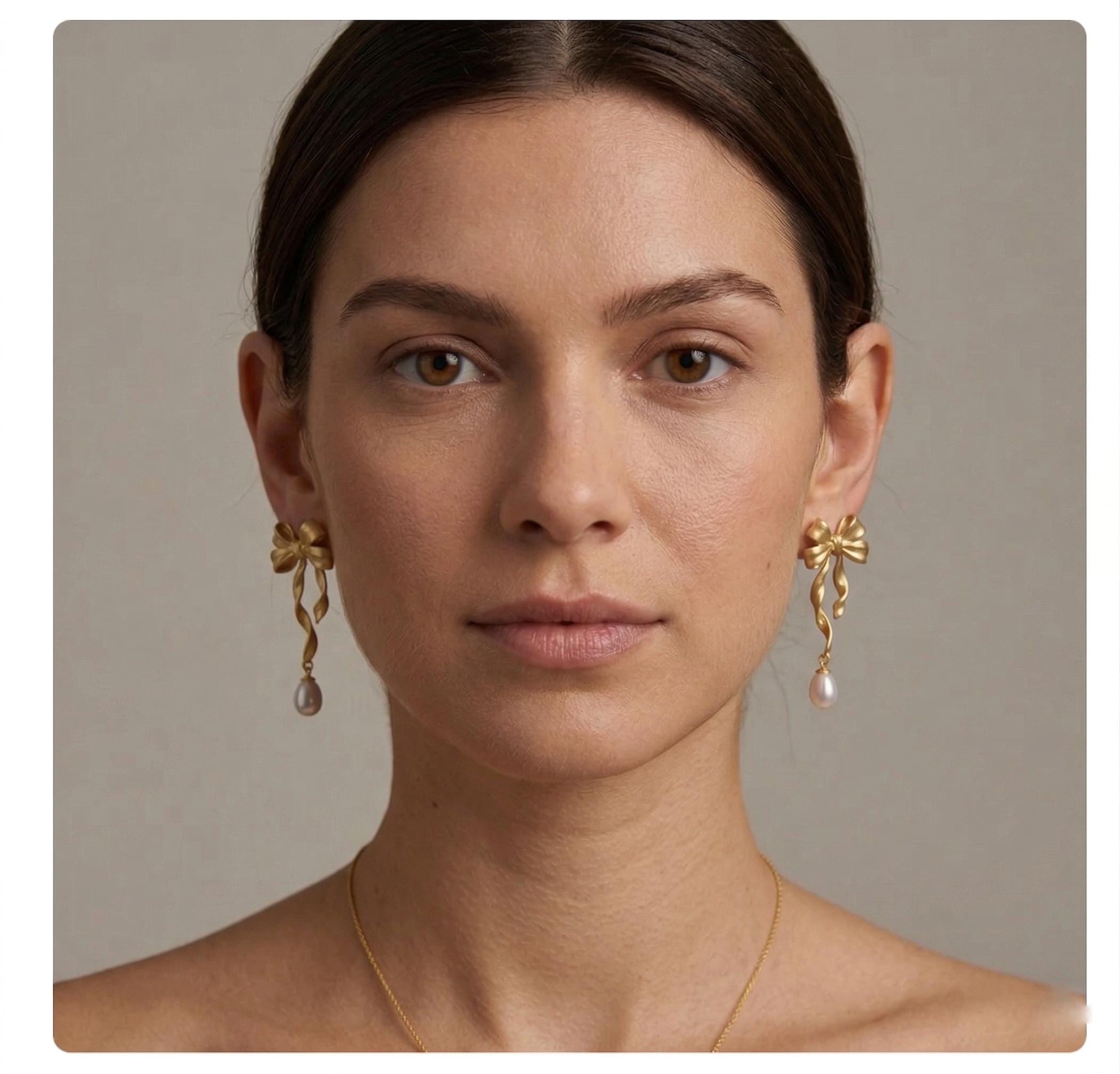 A model wearing Caellia 14K gold bow earrings with dangling freshwater pearls.
