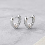 Caellia sterling silver heart huggie hoop earrings featuring a small freshwater pearl.
