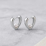 Caellia sterling silver heart huggie hoop earrings featuring a small freshwater pearl.