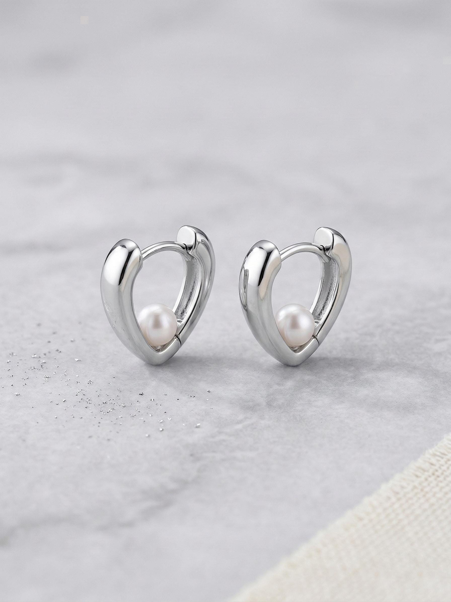 Caellia sterling silver heart huggie hoop earrings featuring a small freshwater pearl.