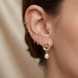 Close-up of gold rose pearl drop stud earring worn with a delicate ear stack