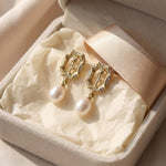 Gold rose pearl drop earrings presented inside a cream jewelry box