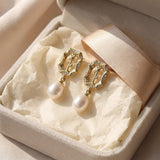 Gold rose pearl drop earrings presented inside a cream jewelry box