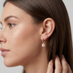 Model wearing 14K gold plated half hoop earrings with white freshwater pearl drops