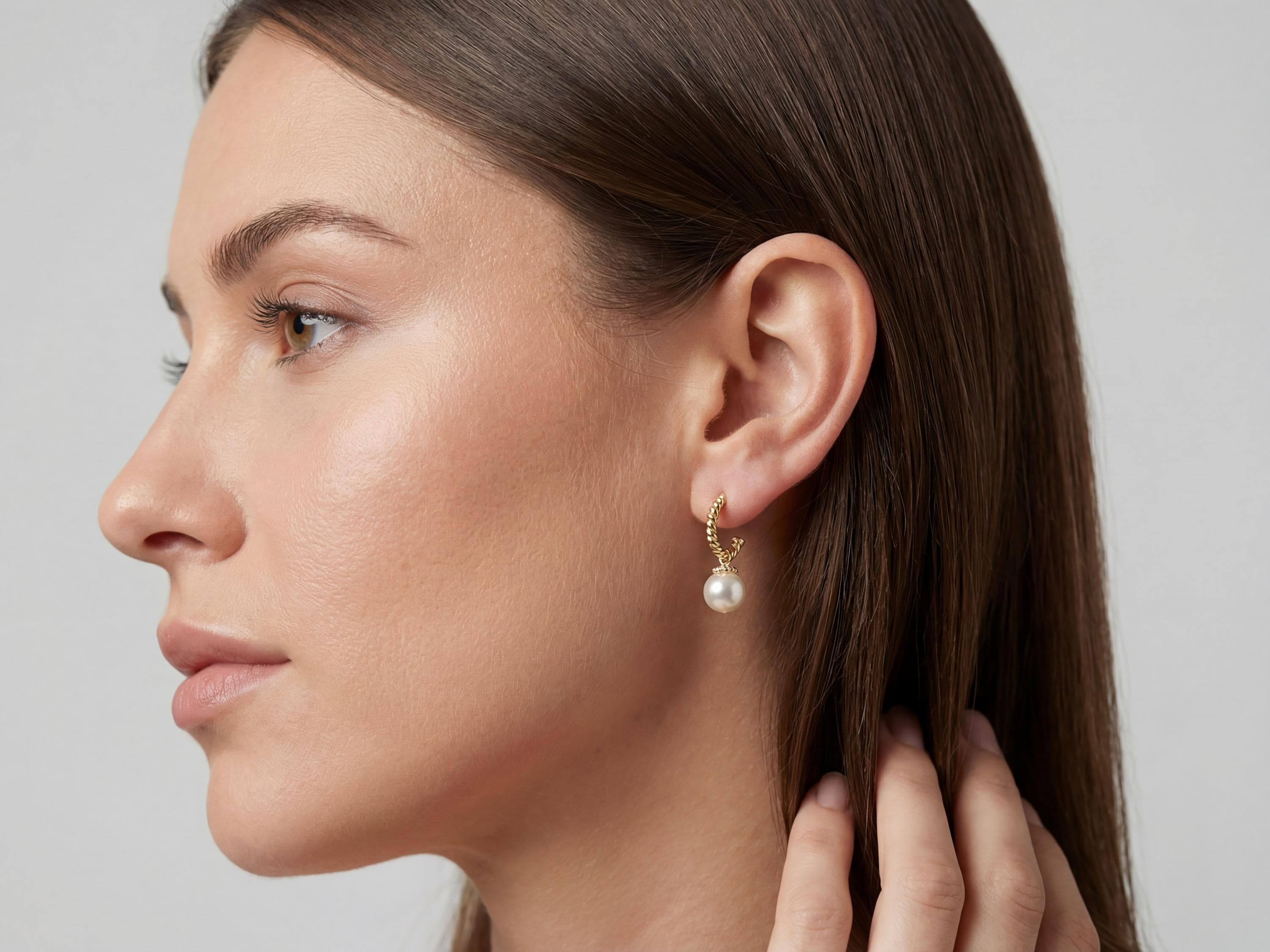 Model wearing 14K gold plated half hoop earrings with white freshwater pearl drops