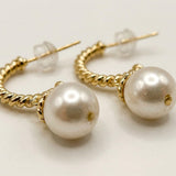 Macro view of white freshwater pearls and twisted gold plated half hoop earring details