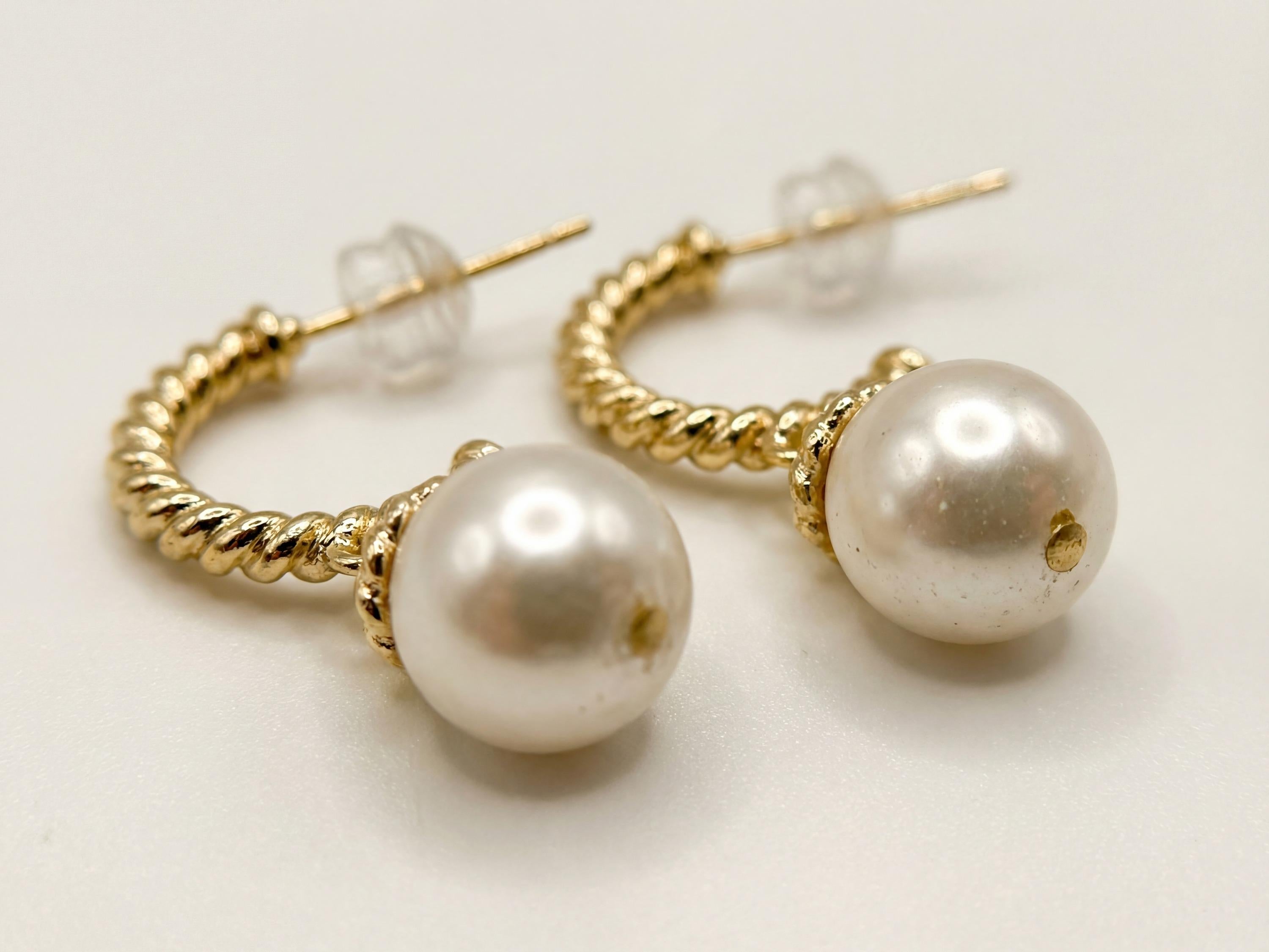 Macro view of white freshwater pearls and twisted gold plated half hoop earring details