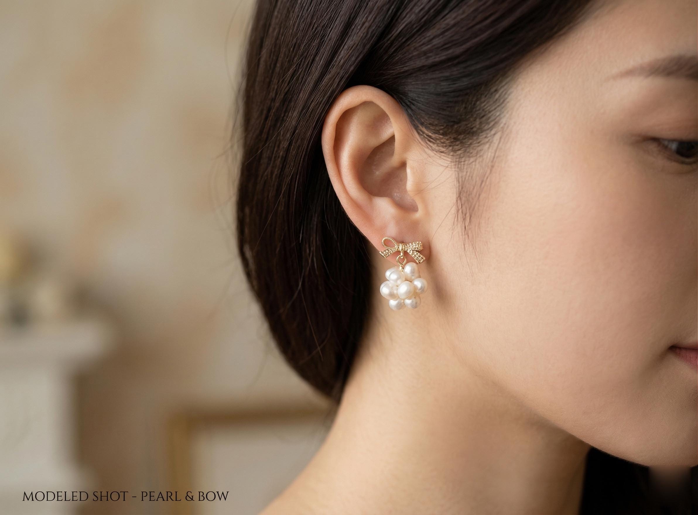 A woman wears the Caellia 14K gold bowknot earrings featuring a cluster of freshwater pearls.