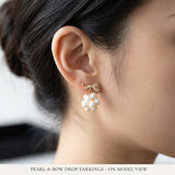 A model wears Caellia 14K gold bowknot earrings featuring a cluster of freshwater pearls.
