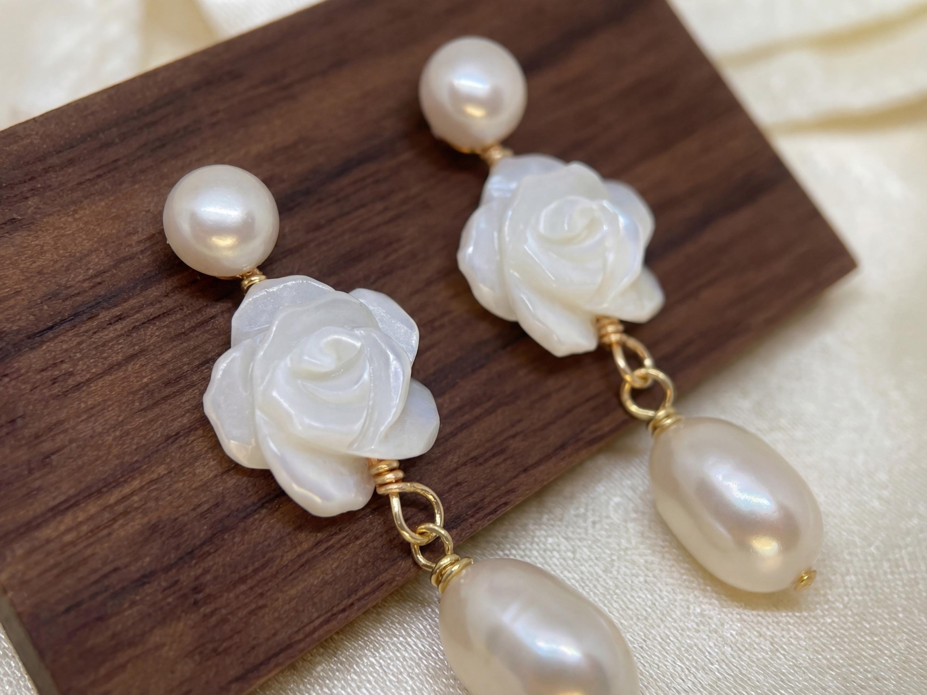 Close up pair of white camellia earrings with round and teardrop pearls