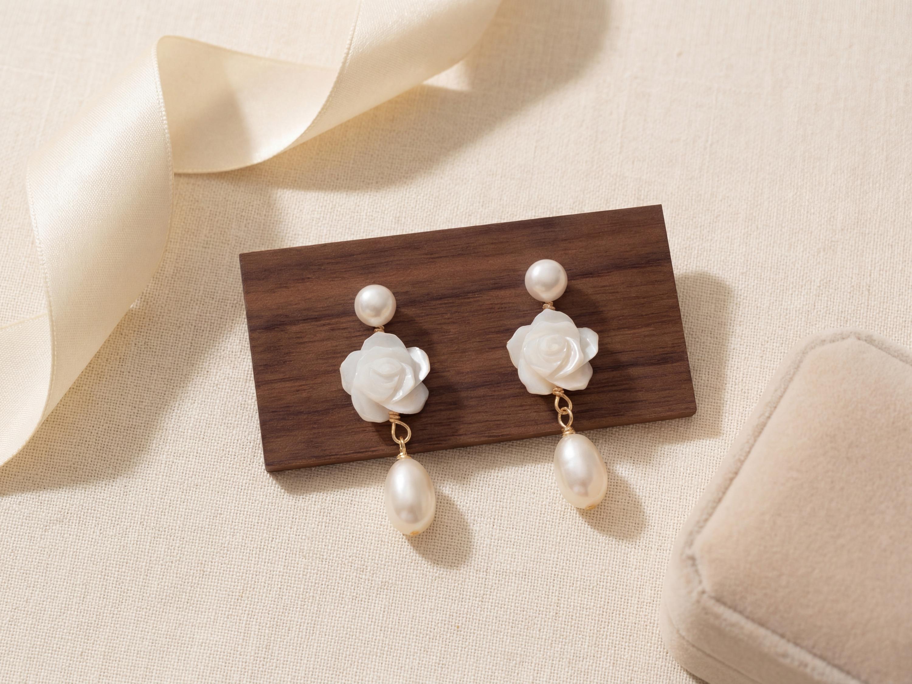 White floral pearl earrings displayed on wood with gift box beside them