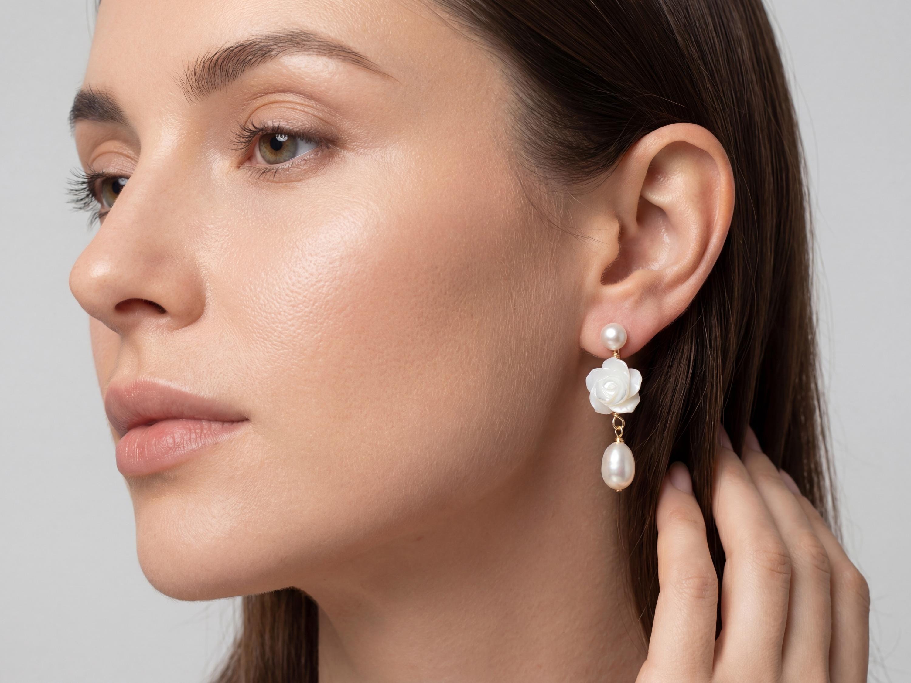 White flower and freshwater pearl dangle earring shown on model for scale