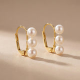 Pair of gold leverback earrings with three round white freshwater pearls on each side
