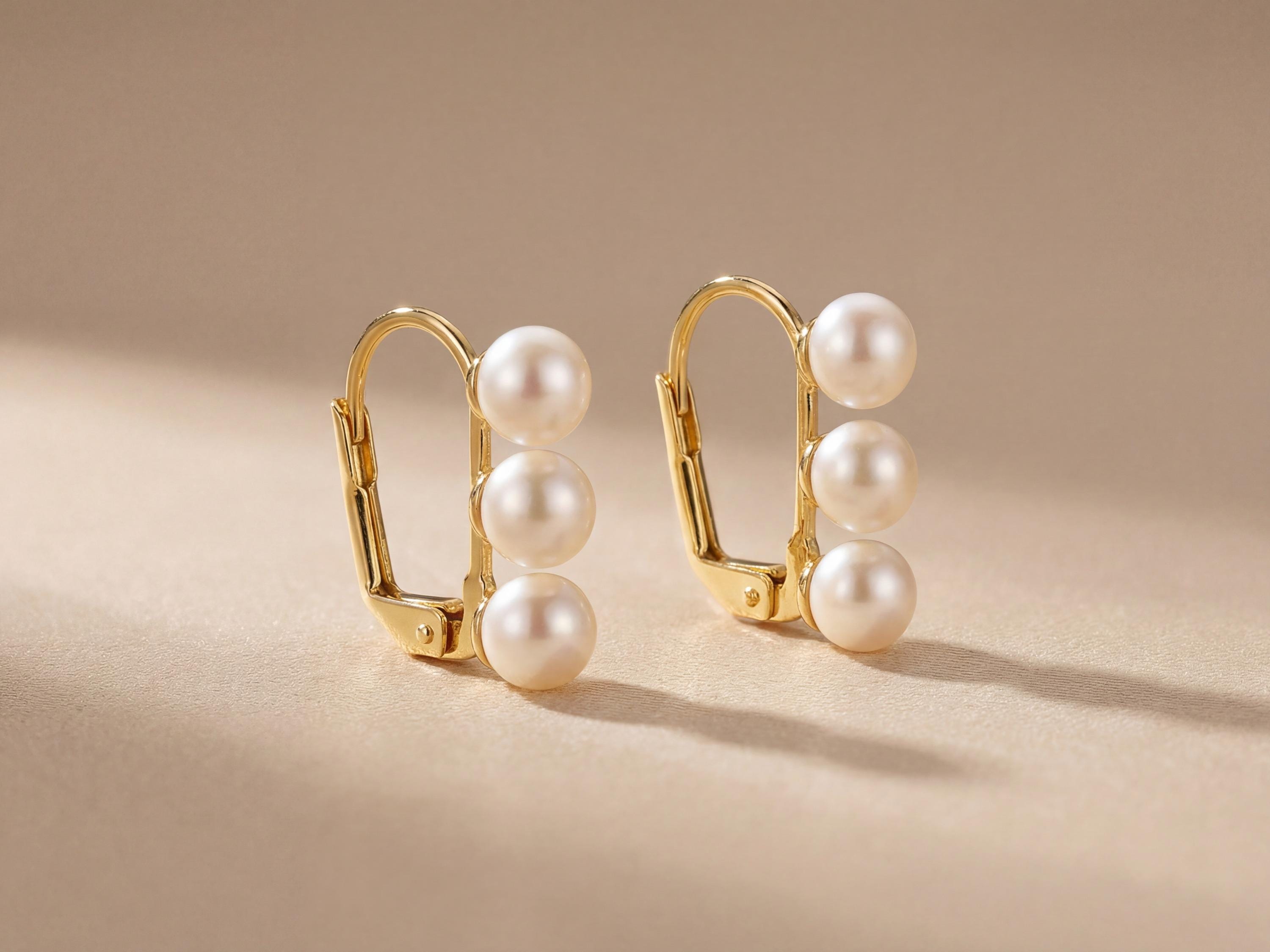 Pair of gold leverback earrings with three round white freshwater pearls on each side