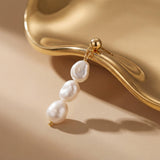 Close-up of one gold plated triple freshwater pearl drop earring styled against a sculptural gold surface