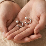 A pair of Caellia freshwater pearl hoop earrings resting in a person's cupped hands.