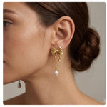 CAELLIA 14K gold bow earrings featuring a dangling freshwater pearl on a model.