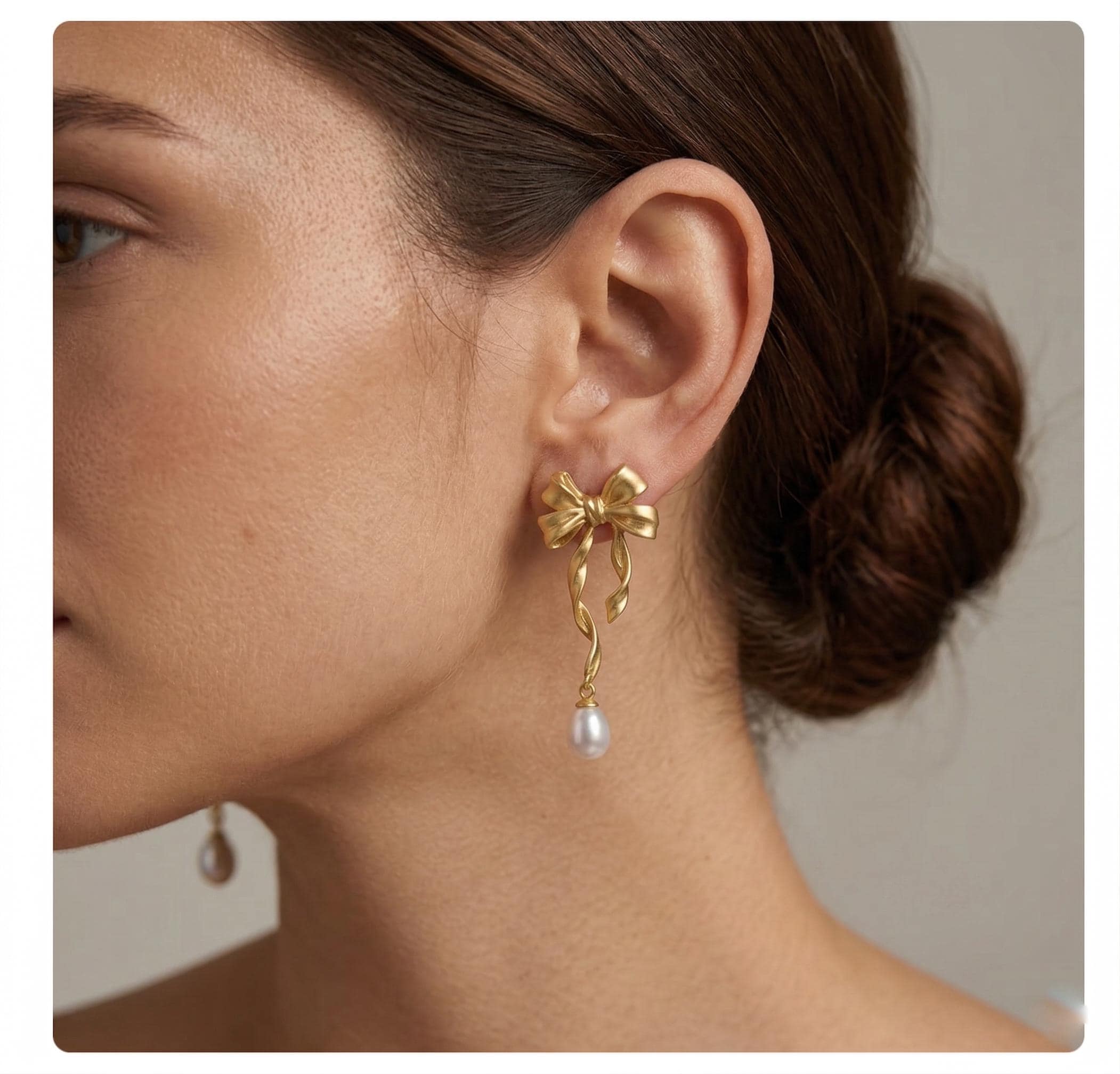 CAELLIA 14K gold bow earrings featuring a dangling freshwater pearl on a model.