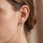 Model wearing a gold rose frame earring with a white freshwater pearl drop