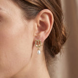 Model wearing a gold rose frame earring with a white freshwater pearl drop