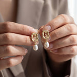 Hands holding matching gold rose freshwater pearl drop earrings