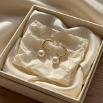 Gold half hoop freshwater pearl earrings presented in a cream jewelry gift box