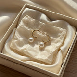 Gold half hoop freshwater pearl earrings presented in a cream jewelry gift box