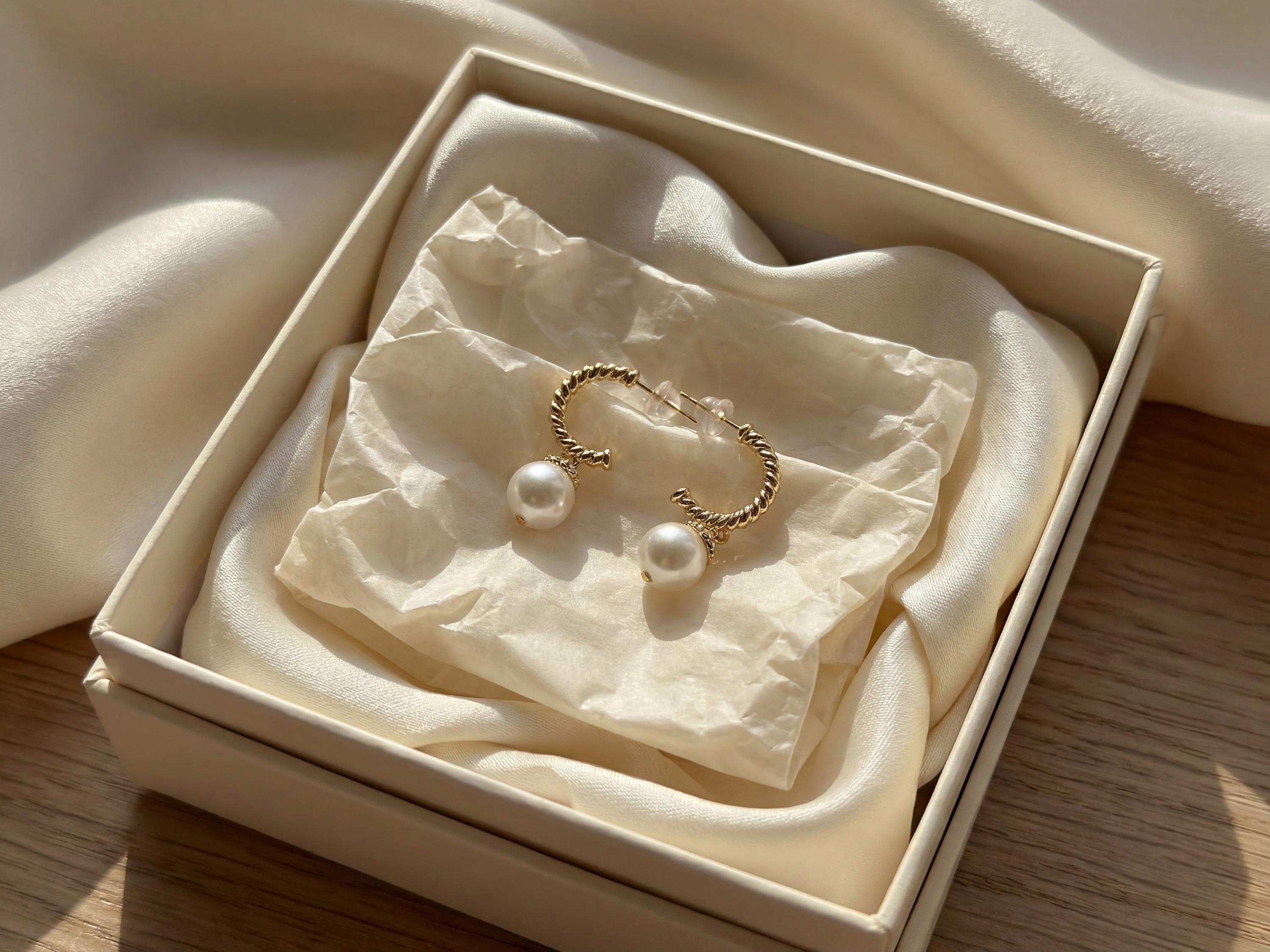 Gold half hoop freshwater pearl earrings presented in a cream jewelry gift box