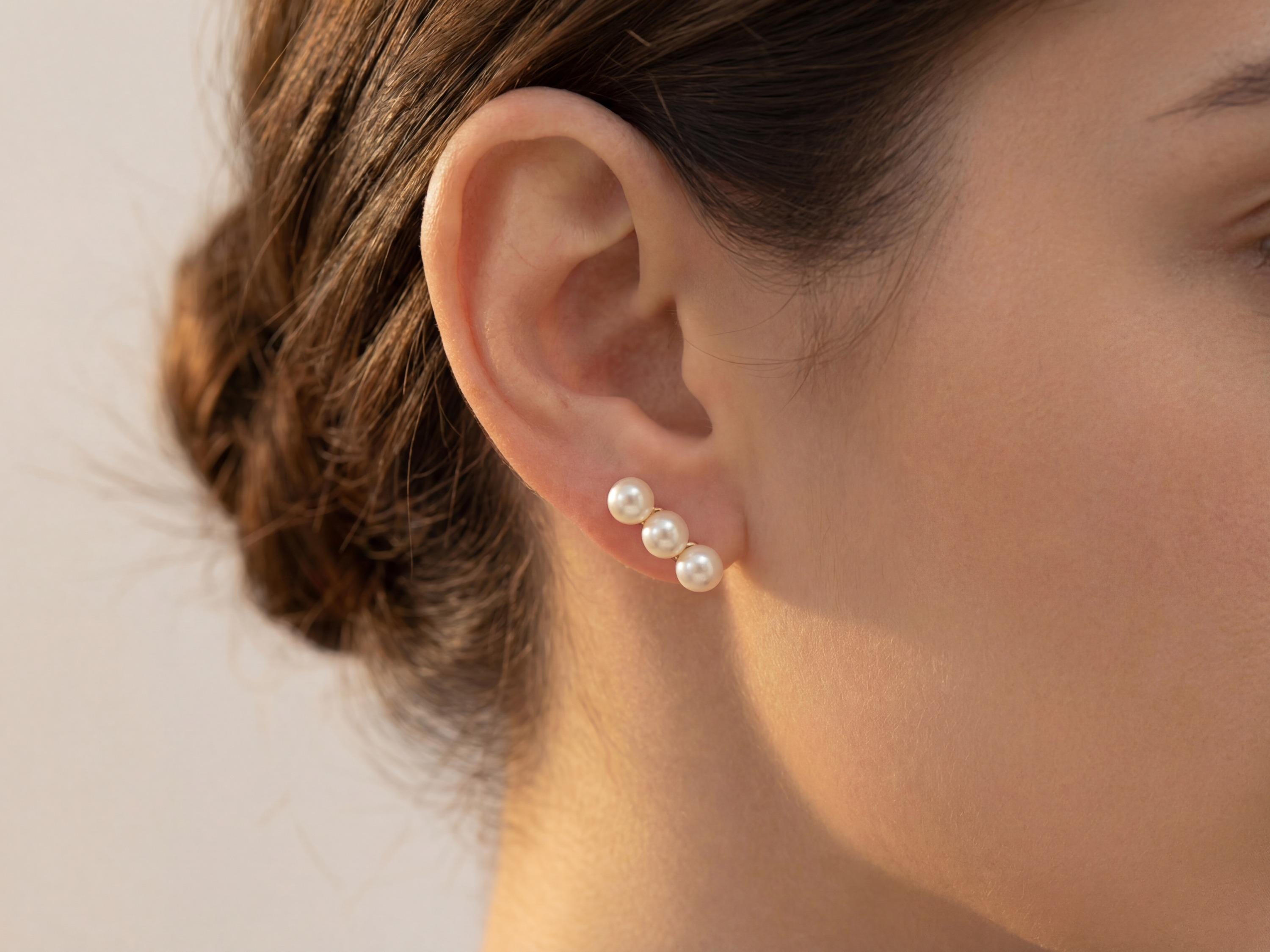 Close-up of triple freshwater pearl leverback earrings worn on ear