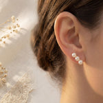 Triple pearl gold leverback earring worn beside dried white flowers