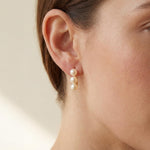 Side profile showing three white pearls arranged vertically on a gold earring