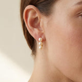 Side profile showing three white pearls arranged vertically on a gold earring