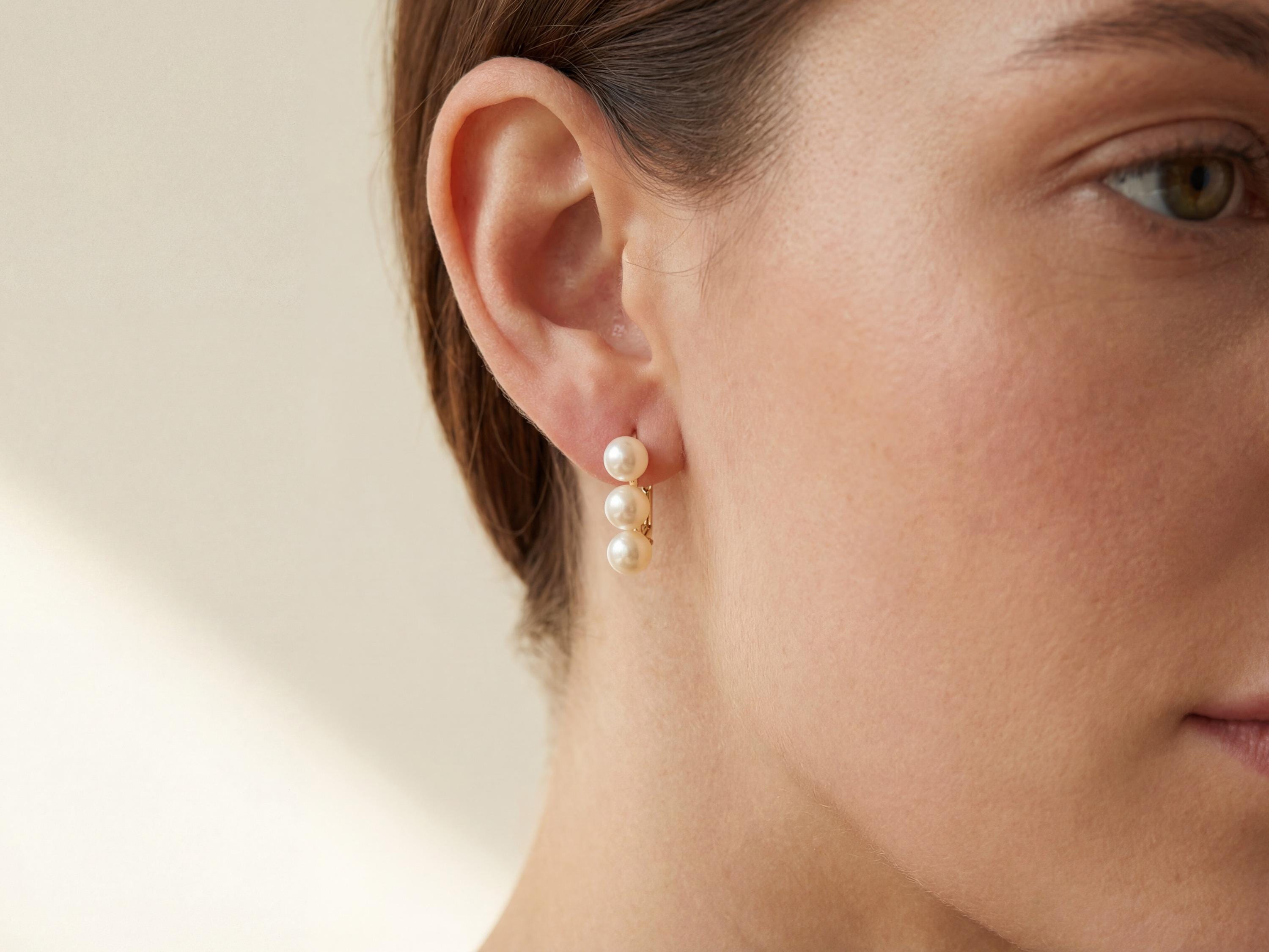 Side profile showing three white pearls arranged vertically on a gold earring