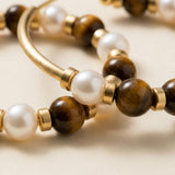 Close up of tiger eye gemstone beads, freshwater pearls, and warm gold tone spacers