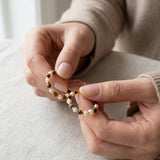 Tiger eye and pearl hoop earrings held in hands to show the beaded design and scale