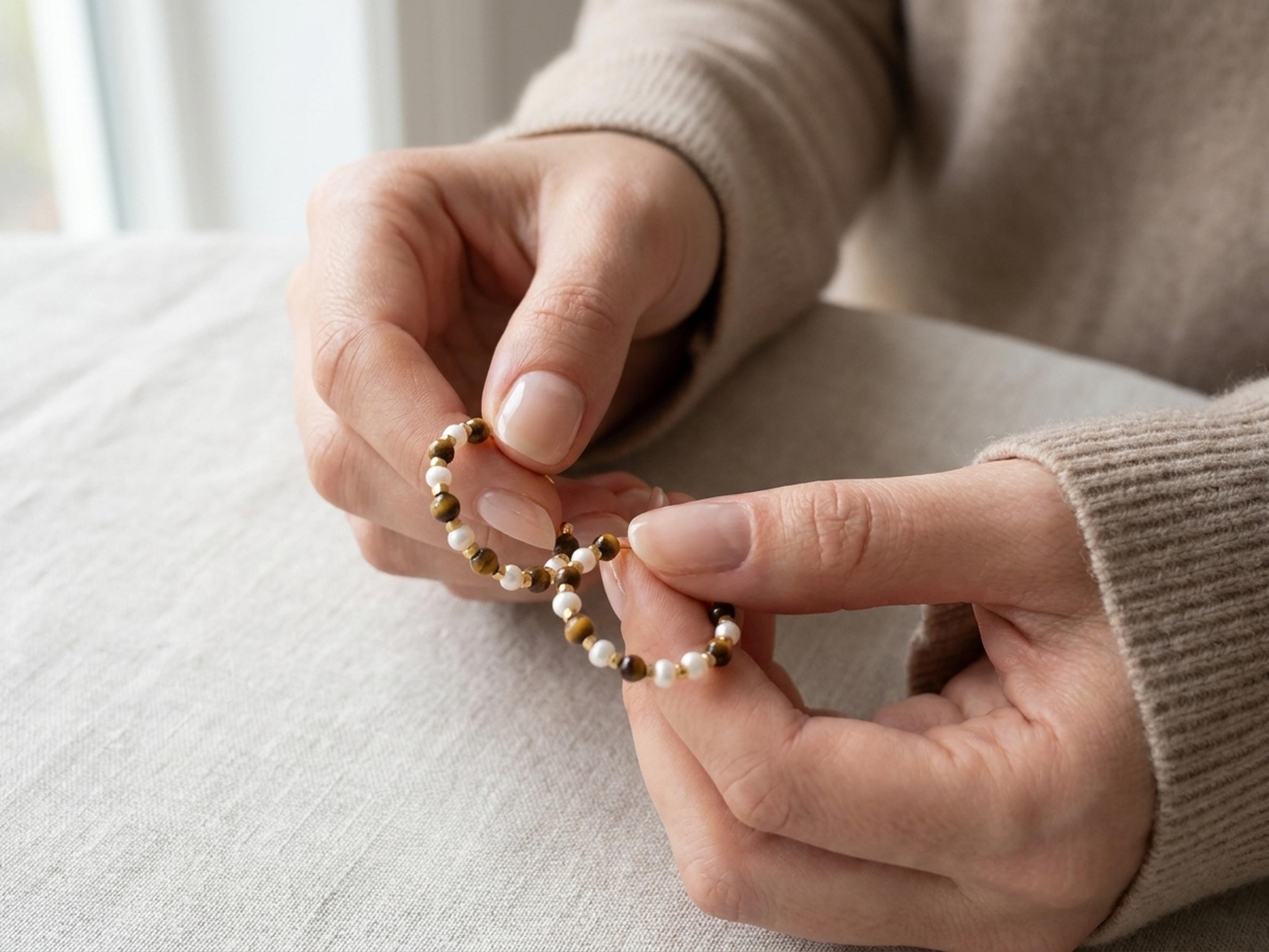 Tiger eye and pearl hoop earrings held in hands to show the beaded design and scale
