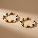 Sculptural close up of tiger eye gemstone and freshwater pearl beaded hoop earrings