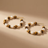 Sculptural close up of tiger eye gemstone and freshwater pearl beaded hoop earrings