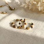 Tiger eye and freshwater pearl hoop earrings styled on cream fabric in warm natural light