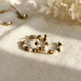 Tiger eye and freshwater pearl hoop earrings styled on cream fabric in warm natural light