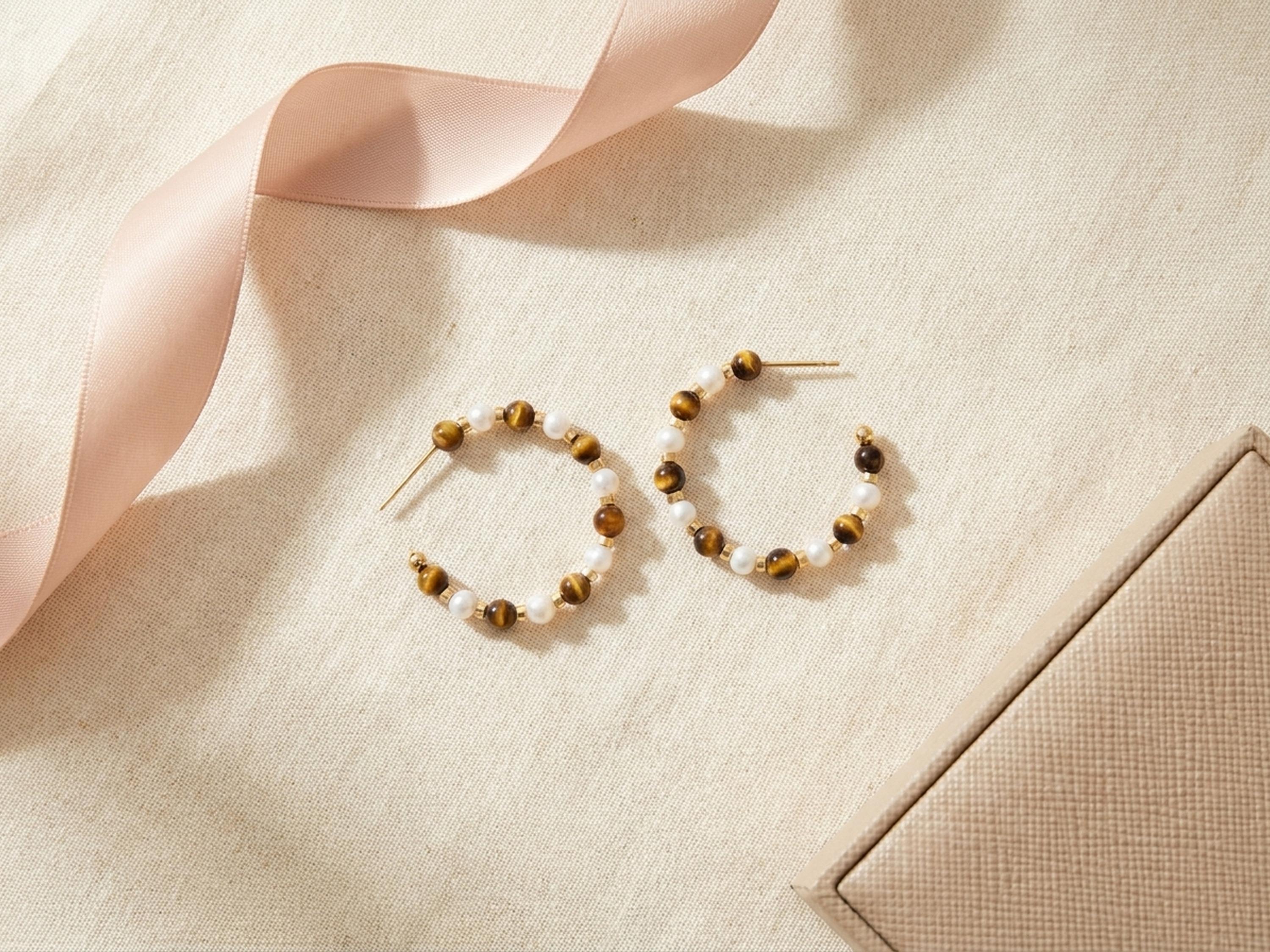 Tiger eye and pearl statement hoop earrings flat lay with blush ribbon and gift box