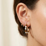 Tiger eye pearl hoop earrings styled with warm gold jewelry for a layered look