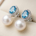 Close-up of oval blue cubic zirconia halo stud earrings with white pearl drops