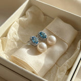 Blue cubic zirconia pearl earrings presented inside a cream gift box