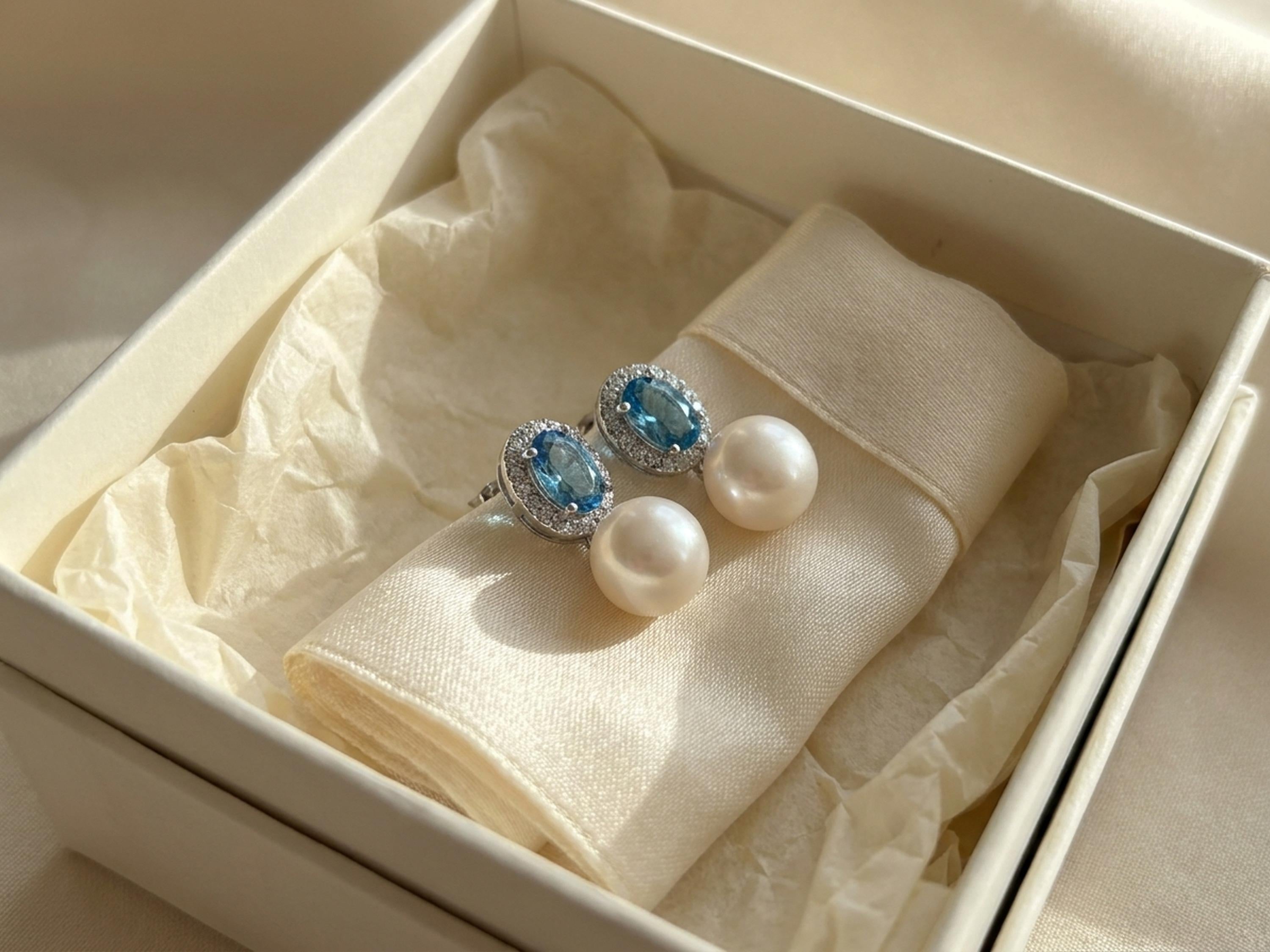 Blue cubic zirconia pearl earrings presented inside a cream gift box