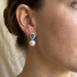 Woman wearing blue cubic zirconia and pearl drop stud earrings in side profile