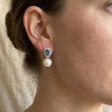 Woman wearing blue cubic zirconia and pearl drop stud earrings in side profile