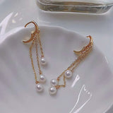 Three pearls tear drop earrings with gold-plated chains on a white surface.
